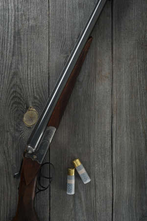 Hunting rifle and hunting accessories on the table. Vintage hunting gun with cartridges on wooden background. top view.の写真素材