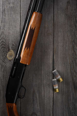 Hunting rifle and hunting accessories on the table. Vintage hunting gun with cartridges on wooden...