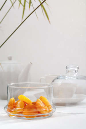 Dried apricots in a glass vase, a teapot and a ceramic cup on a white table. light background.の写真素材