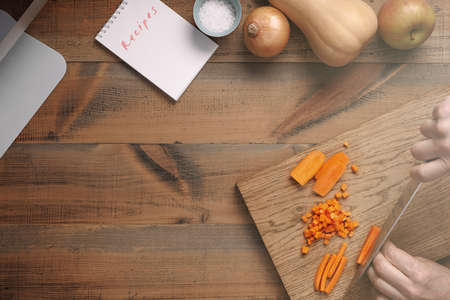 A man cuts carrots on a wooden cutting board. top view.