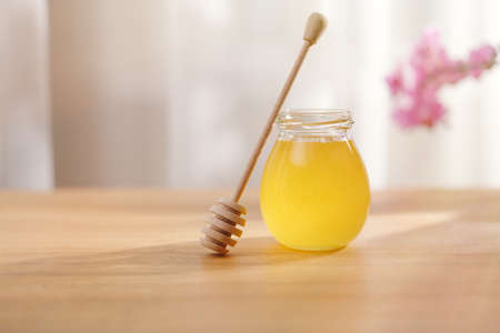 Honey background. Sweet honey in a glass jar and a honey spoon on a wooden table.