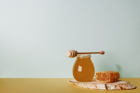 Honey background. Sweet honey in a glass jar and a honey spoon on a wooden table. Copy space for your textの写真素材