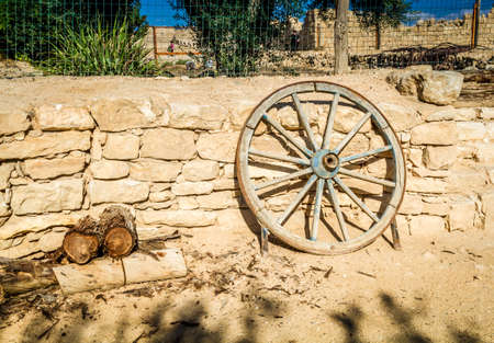 Old wooden wheel with an iron rim leaning up against a ancient stone wallの写真素材