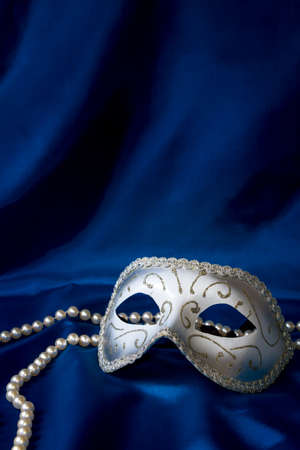 Silver carnival mask and pearl on dark blue silk backgroundの写真素材