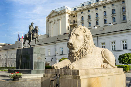 WARSAW, POLAND - SEPTEMBER 17: Stone statue of a lion lying in front of the Presidential Palace, behind it is a monument to Prince Jozef Poniatowski in Warsaw, Poland on September 17, 2016のeditorial素材