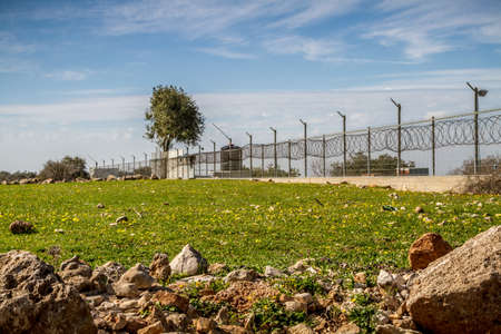 Fence with razor wire on top of fencing surrounds industrial areaの写真素材