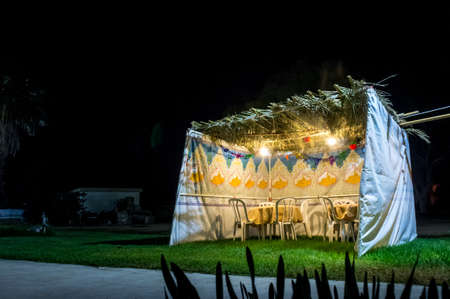 Fabric sukkah decorated with printed pattern and hebrew text of blessing: Grant peace everywhere goodness and blessing, Grace, lovingkindness and mercy to us and unto all Israel, Your people. Nightの写真素材