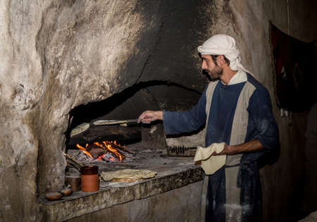 NAZARETH, ISRAEL - DECEMBER 16: Man dressed in period clothes bakes bread in Nazareth Village, Israel on December 16, 2016のeditorial素材
