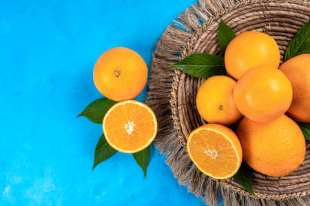 A few ripe oranges with leaves on a blue wooden background, top view, copy space.の写真素材