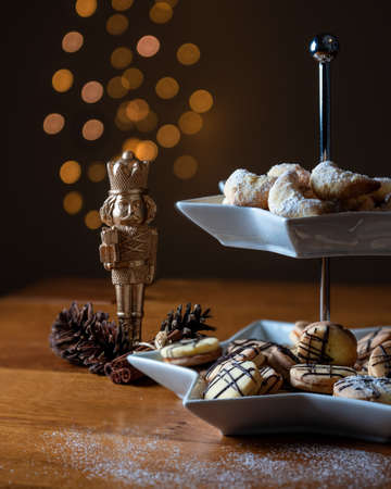 Christmas cookies, nutcracker, pine cones and cinnamon sticks on a wood table. Fairy lights...