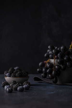 blackberries, blueberries and grapes on a black background. Front view, copy space.の写真素材