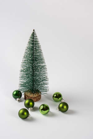Beautiful miniature Christmas tree with green Christmas balls over a white background. Copy space, front view.の写真素材