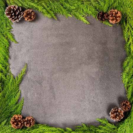Christmas composition with frame of fir branches and pine cones on a gray background. Flat lay, top view, copy space.の写真素材