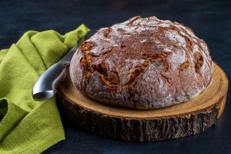 Freshly baked traditional country style wheat rye wholemeal bread. Single object on a wooden...