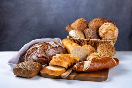Delicious freshly baked buns and bread on a white table and rustic background. Front view, copy space.の写真素材
