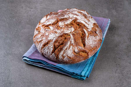 Traditional wholemeal rye bread in country style. Single object on a checkered napkin. Top view, copy space.の写真素材
