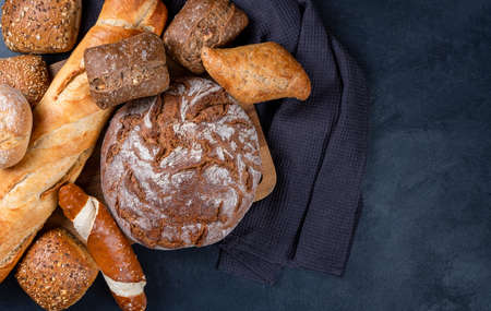 Delicious freshly baked bread on a rustic background with a dark napkin. Top view, copy spaceの写真素材