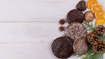 Different types of gingerbread cookies on a white table with pine cones and branch, anise star and cinnamon sticks. Top view, copy spaceの写真素材