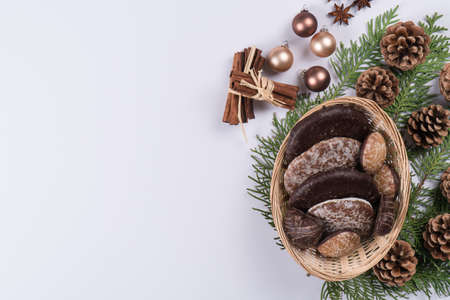 Gingerbread cookies on a white table with pine cones and branch, anise star and cinnamon sticks. Top view, copy space.の写真素材