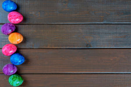 Colored easter eggs on a wooden background, top view, copy space.の写真素材