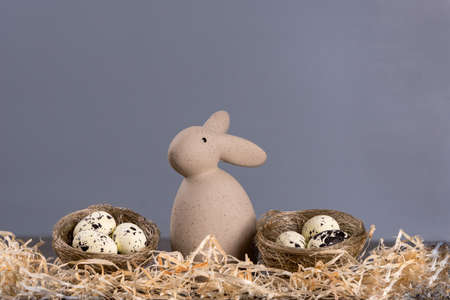 Easter bunny with small nests and eggs on a gray background. Easter concept. copyspace.の写真素材