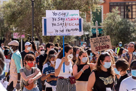 Palma de Mallorca, Spain - June 07 2020: young women surrounded by crowd with placards protesting...