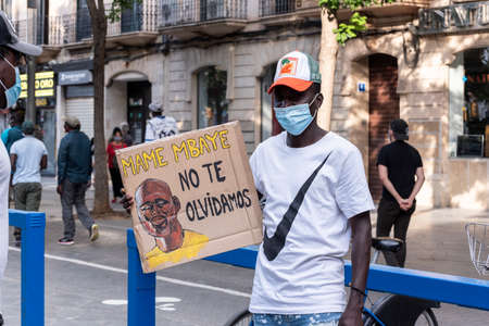 Palma de Mallorca, Spain - June 07 2020: Palma de Mallorca, Spain - June 07 2020: Young man holding a placard with drawing in memory of Mame Mbaye "we will never forget you" in protest against racismのeditorial素材