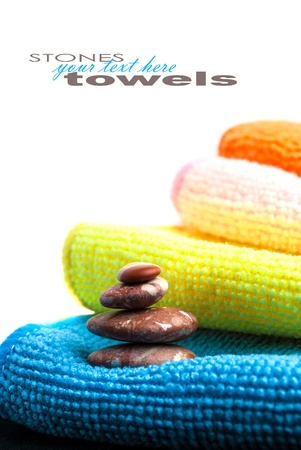 Closeup stack of colorful towels and stones on white background. Space for your text.の写真素材
