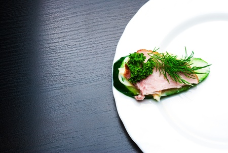 Closeup of delicious ham and cucumber canapes sandwiches with parsley lying on a white plate.の写真素材