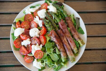 Asparagus wrapped in bacon with saladの写真素材