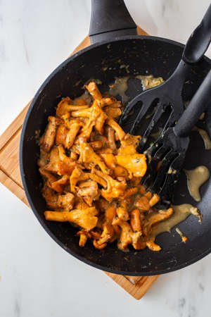 Fried chanterelle mushrooms with onions and rosemary on a dark wooden backgroundの写真素材