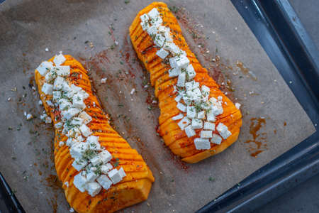 baked hasselbeck butternut pumpkin with feta cheese and fresh herbsの写真素材