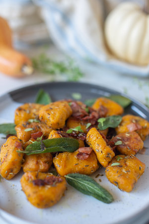 Healthy home made pumpkin gnocchi with cheese and fresh herbs on a tableの写真素材