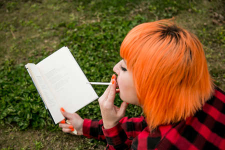 Orange hair girl smoking and readingの写真素材