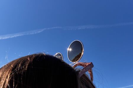 sunglasses on the girl's head and blue skyの写真素材