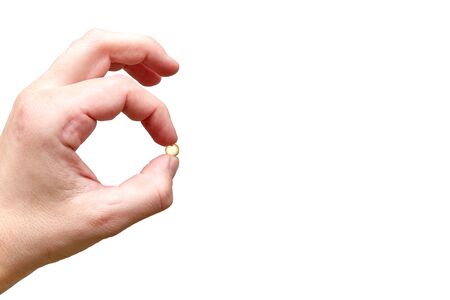 hand holds one tablet in fingers on a white backgroundの写真素材