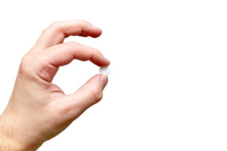 hand holds one tablet in fingers on a white backgroundの写真素材