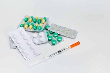 medicines in a package and a syringe lie on a white backgroundの写真素材
