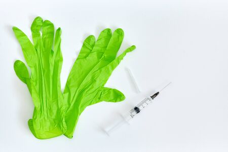 green syringe and medical gloves on a white backgroundの写真素材