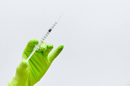 hand in a medical glove holds a syringe whie backgroundの写真素材
