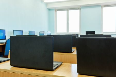 a row of laptops stands on the tables in the office daylightの写真素材