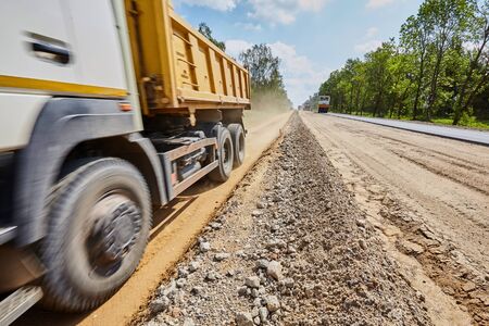 Construction of a road with rubble and sand and a truck on a sunny dayの写真素材