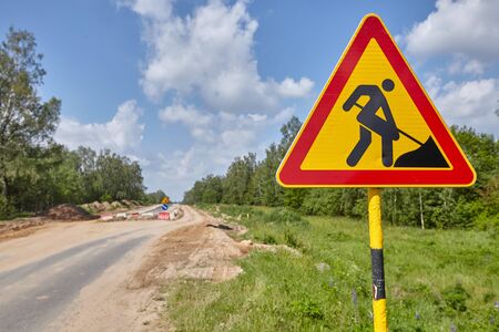 Road sign road repair on the background of the road on a sunny dayの写真素材