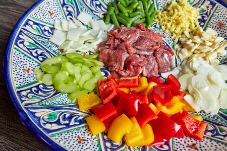 Meat, vegetables and cheeses are cut and lie on a colored plateの写真素材
