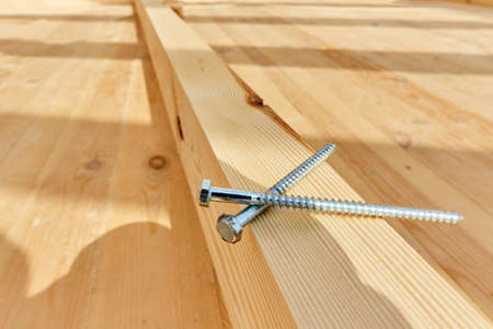 The screws lie on a wooden board sunny dayの写真素材
