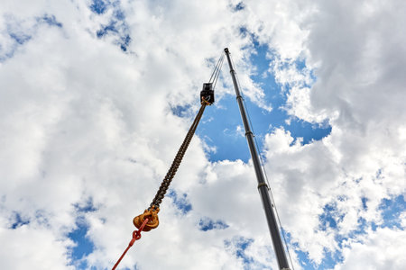 truck crane with outstretched boom on blue sky background sunny day