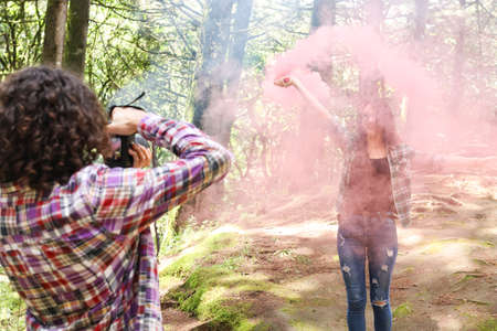 Anonymous profesional Photographer taking photographs of model in the forest holding a red smoke bomb at Costa Ricaの写真素材