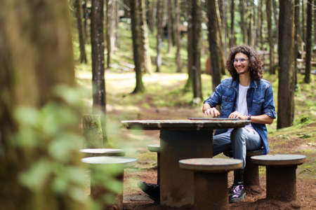 Young latin man sitting in the forest closing laptop smiling at Costa Ricaの写真素材