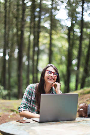 Young latin woman sitting in the forest working with laptop freelancing smiling at Costa Ricaの写真素材