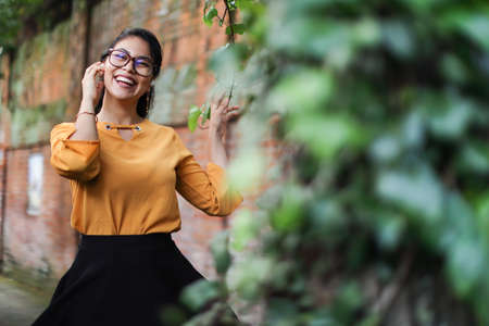 Young brunette latin american woman wearing eyeglasses and earbuds smiling with leaves copy spaceの写真素材